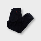 Black Nike trackpants featuring side snap buttons and a red embroidered logo