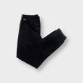 Lacoste black trackpants featuring white side piping and a green crocodile patch near the waist