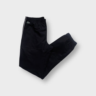 Lacoste black trackpants featuring white side piping and a green crocodile patch near the waist