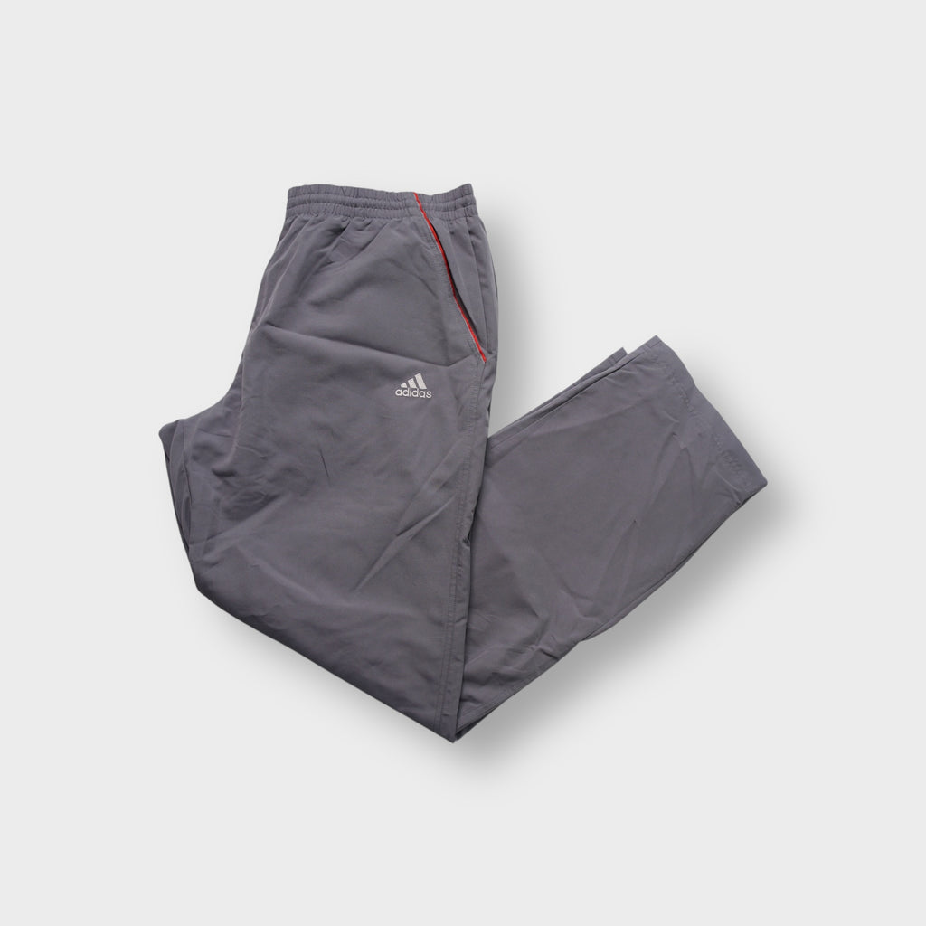 Grey Adidas trackpants showing red side piping and embroidered logo