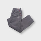Grey Adidas trackpants showing red side piping and embroidered logo