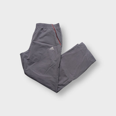Grey Adidas trackpants showing red side piping and embroidered logo