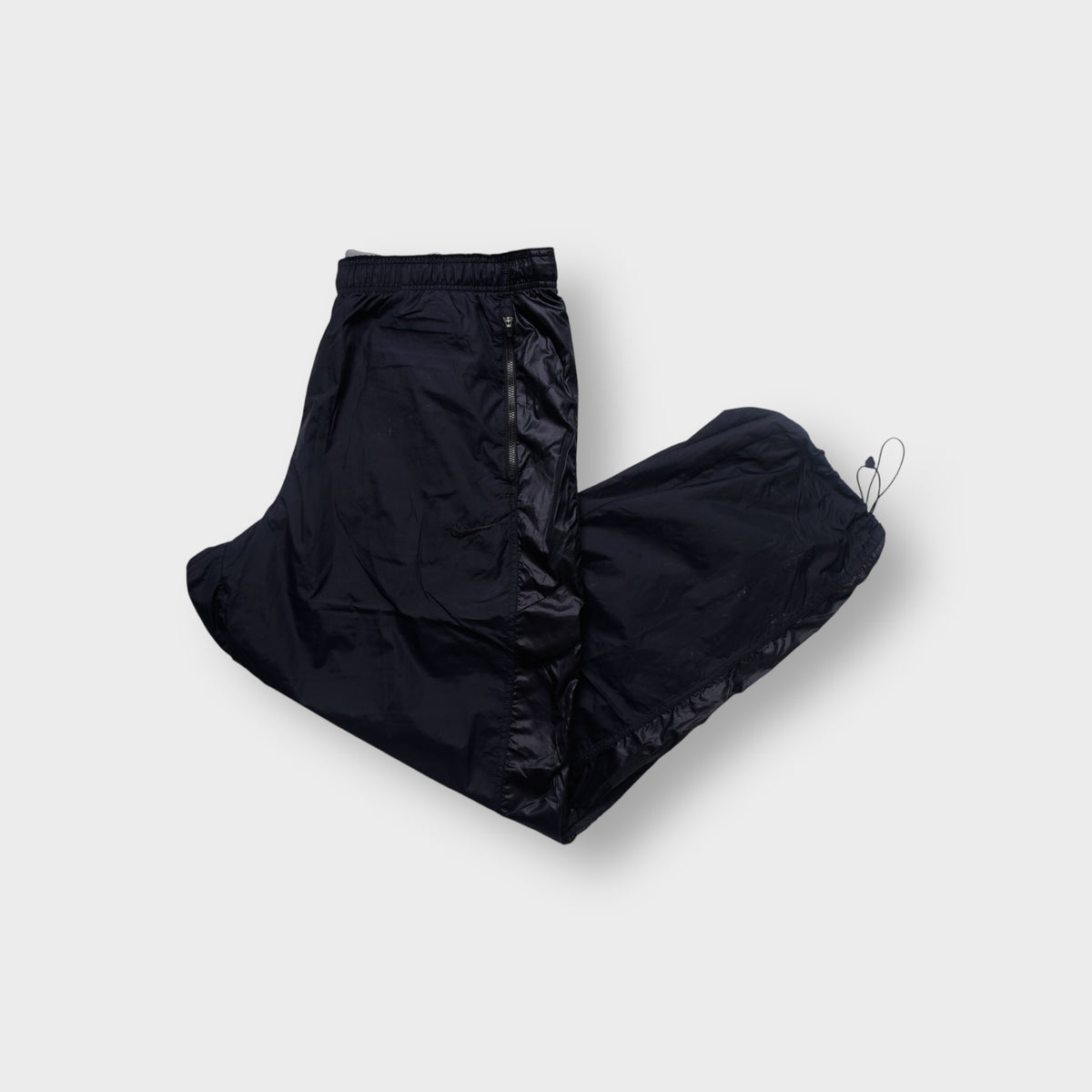 Nike trackpants in black featuring a tonal embroidered swoosh and ankle drawstrings.