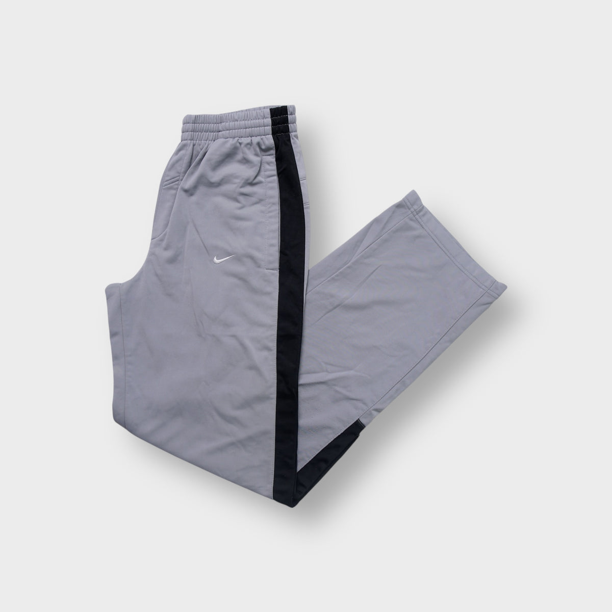Grey Nike trackpants with dark side stripes and small white embroidered swoosh logo