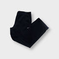 Black Nike trackpants with small white embroidered Swoosh logo near the pocket.