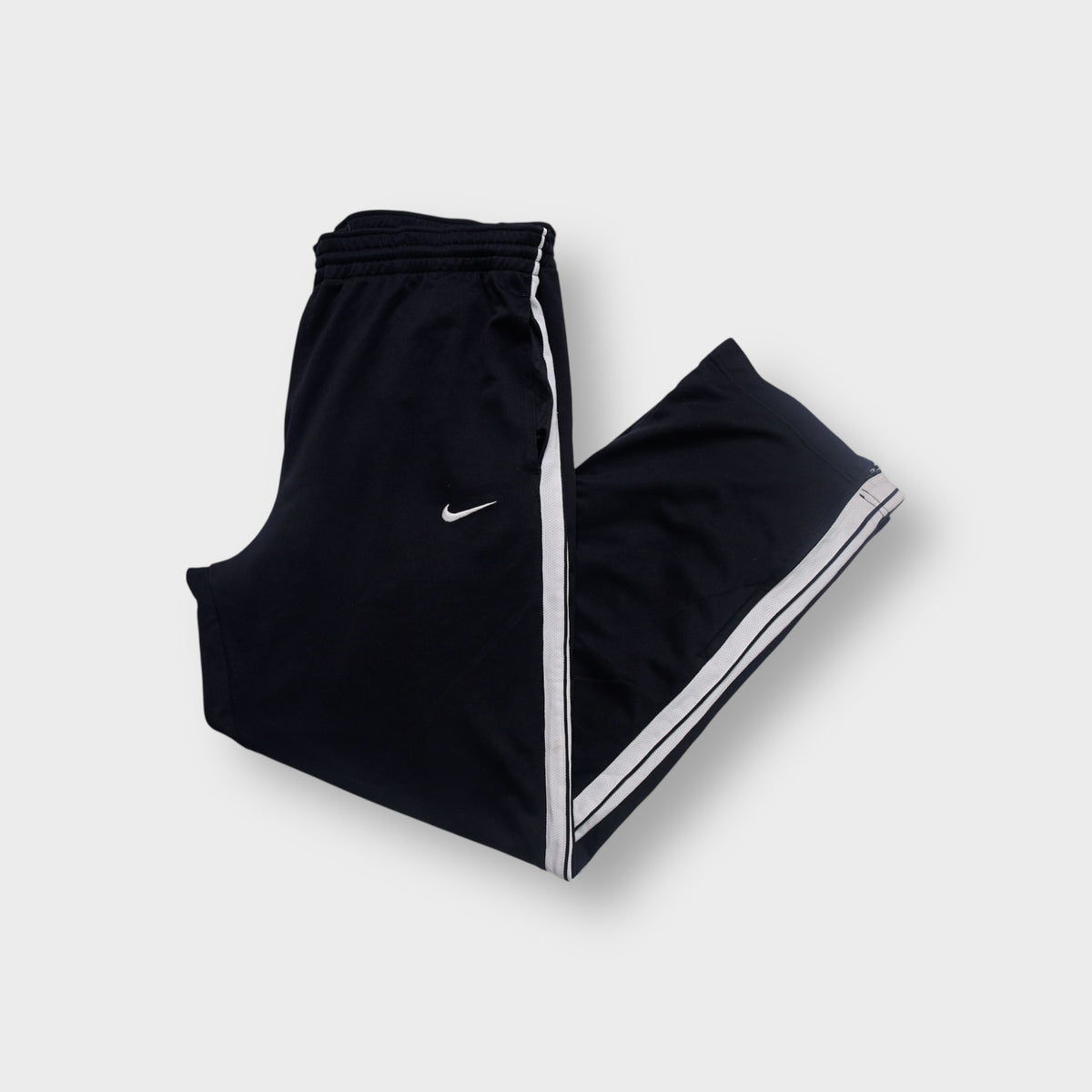 Black Nike trackpants with white side stripes and embroidered swoosh