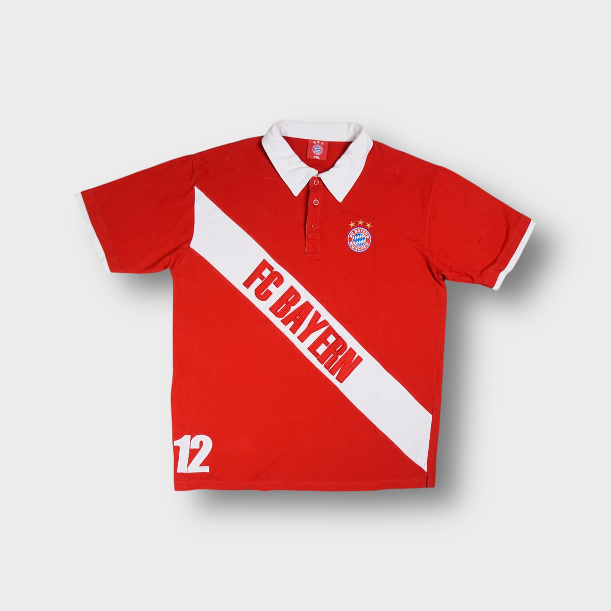 FC Bayern polo shirt in red with white collar, diagonal sash text, and embroidered crest.