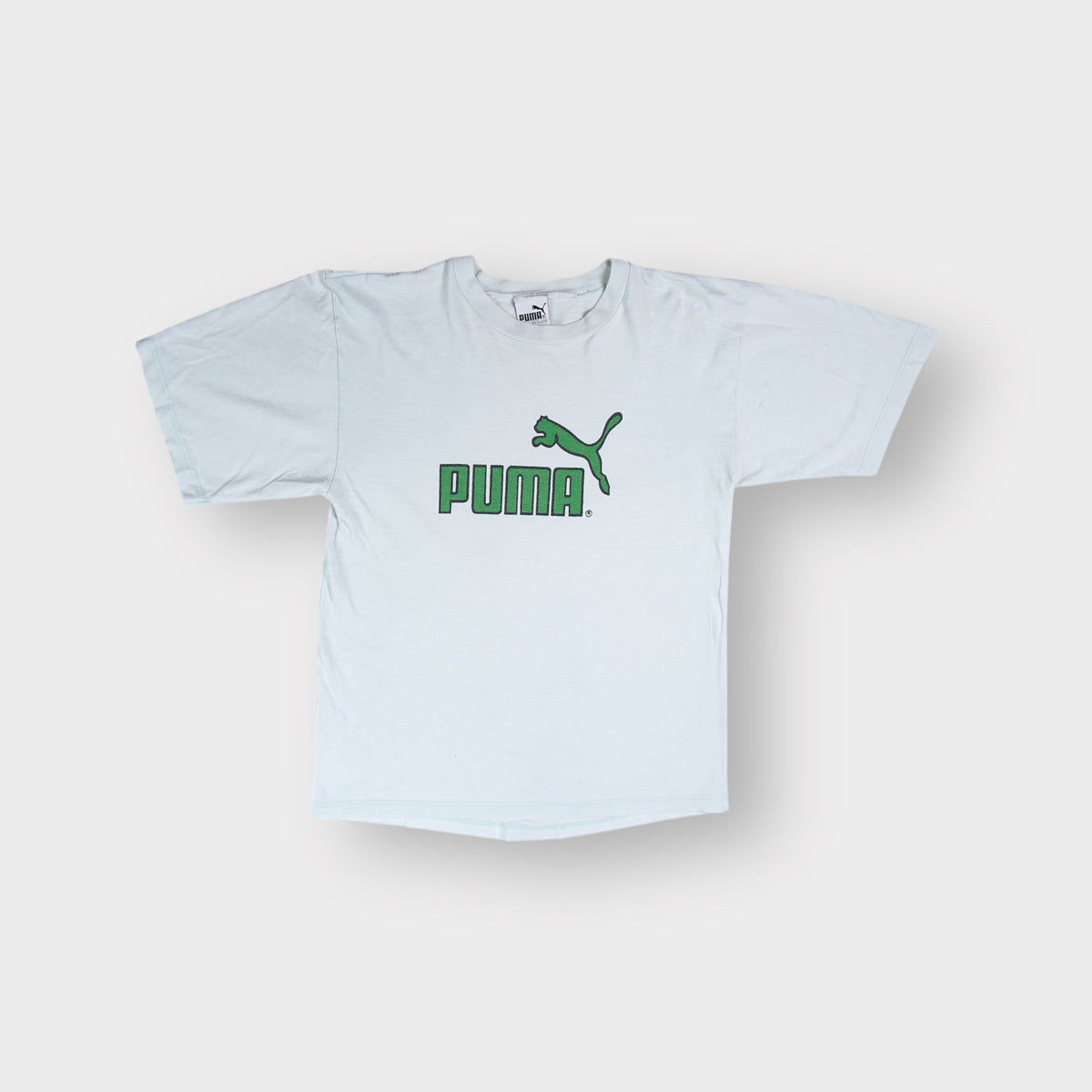 Puma short-sleeve T-shirt in white featuring a green printed cat logo on the chest.