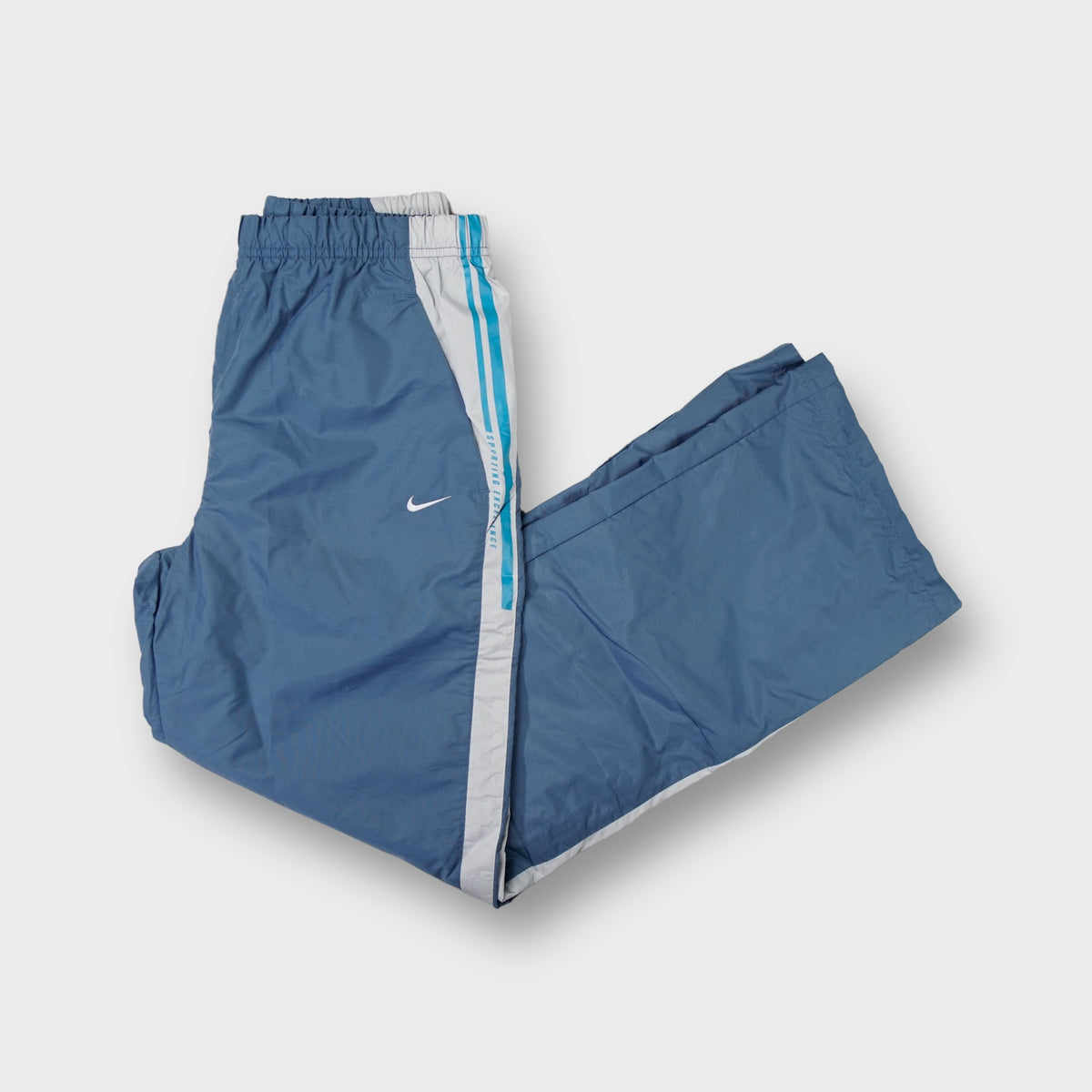 Nike blue trackpants with white side stripes and embroidered swoosh logo