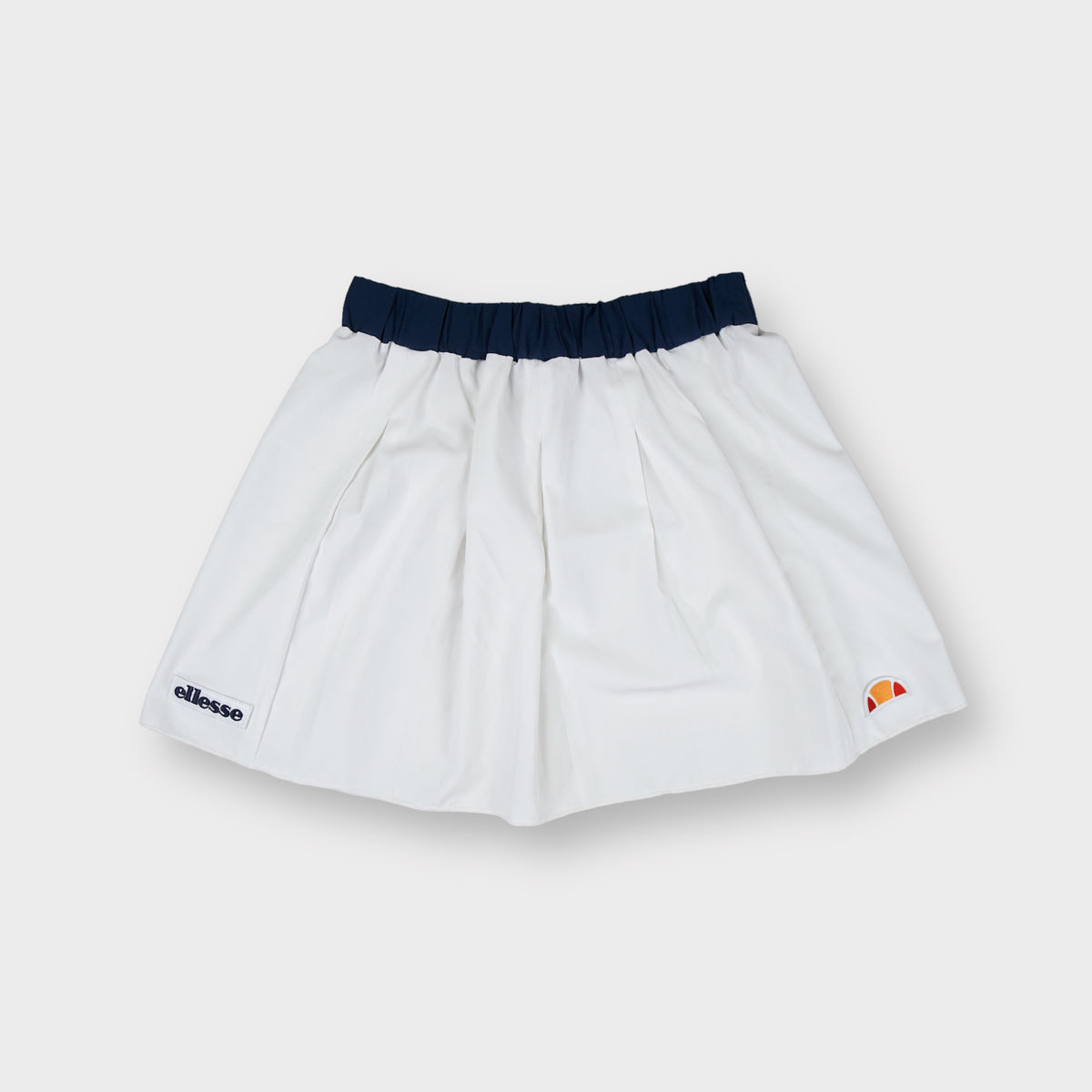 Ellesse tennis skirt in white with dark blue waistband and lower hem logo patches