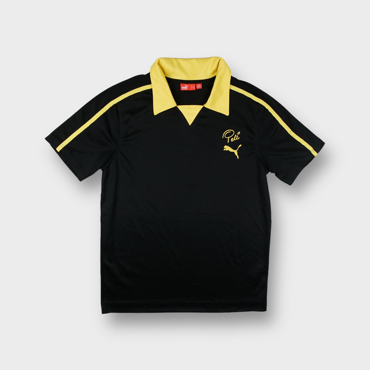 Puma short-sleeve shirt in black with a yellow collar and Pelé embroidered chest logo.