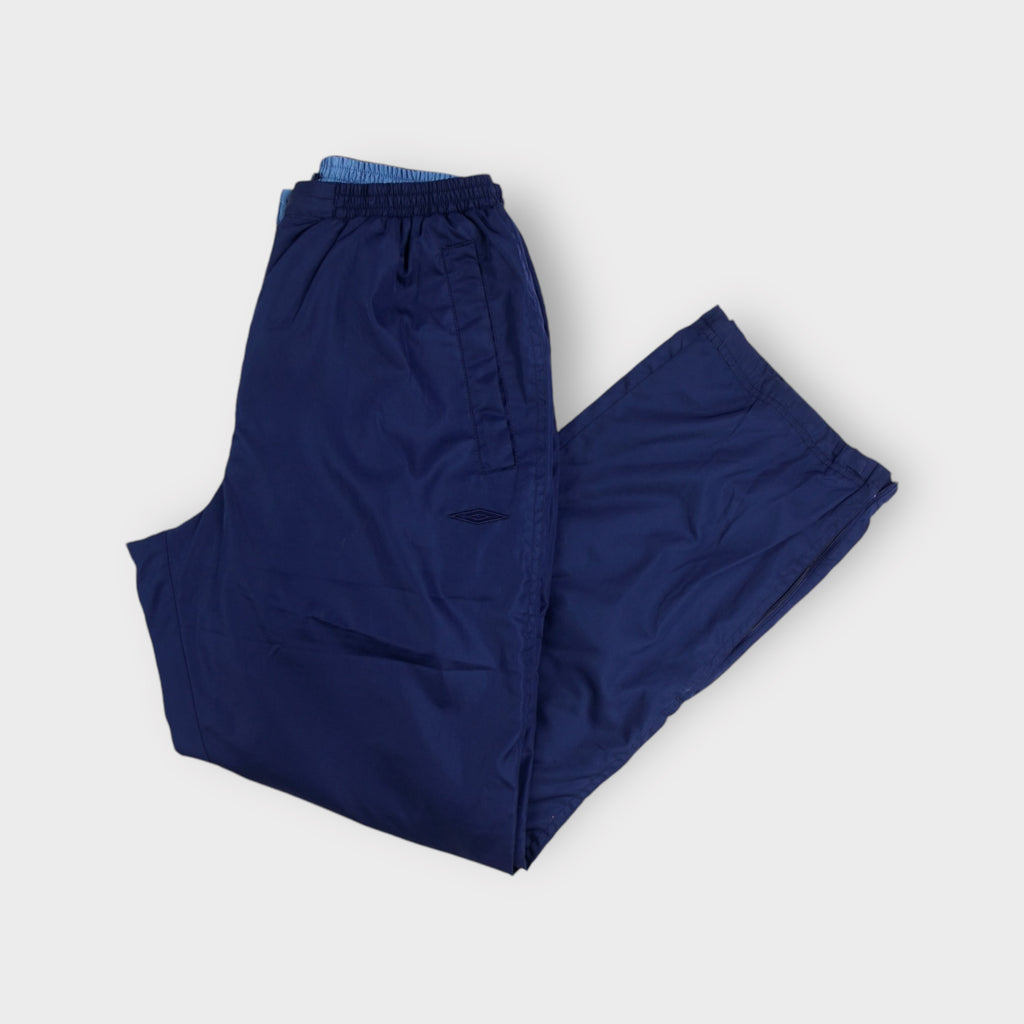 Blue Umbro trackpants featuring a tonal embroidered diamond logo on the upper thigh.