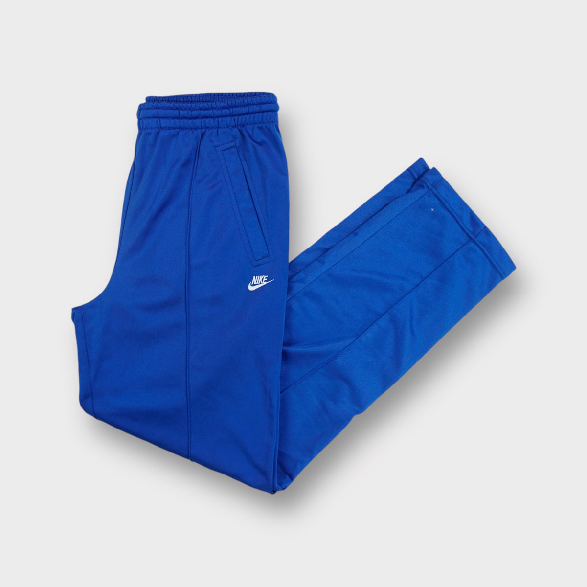 Nike trackpants in bright blue featuring an embroidered white swoosh logo on the hip