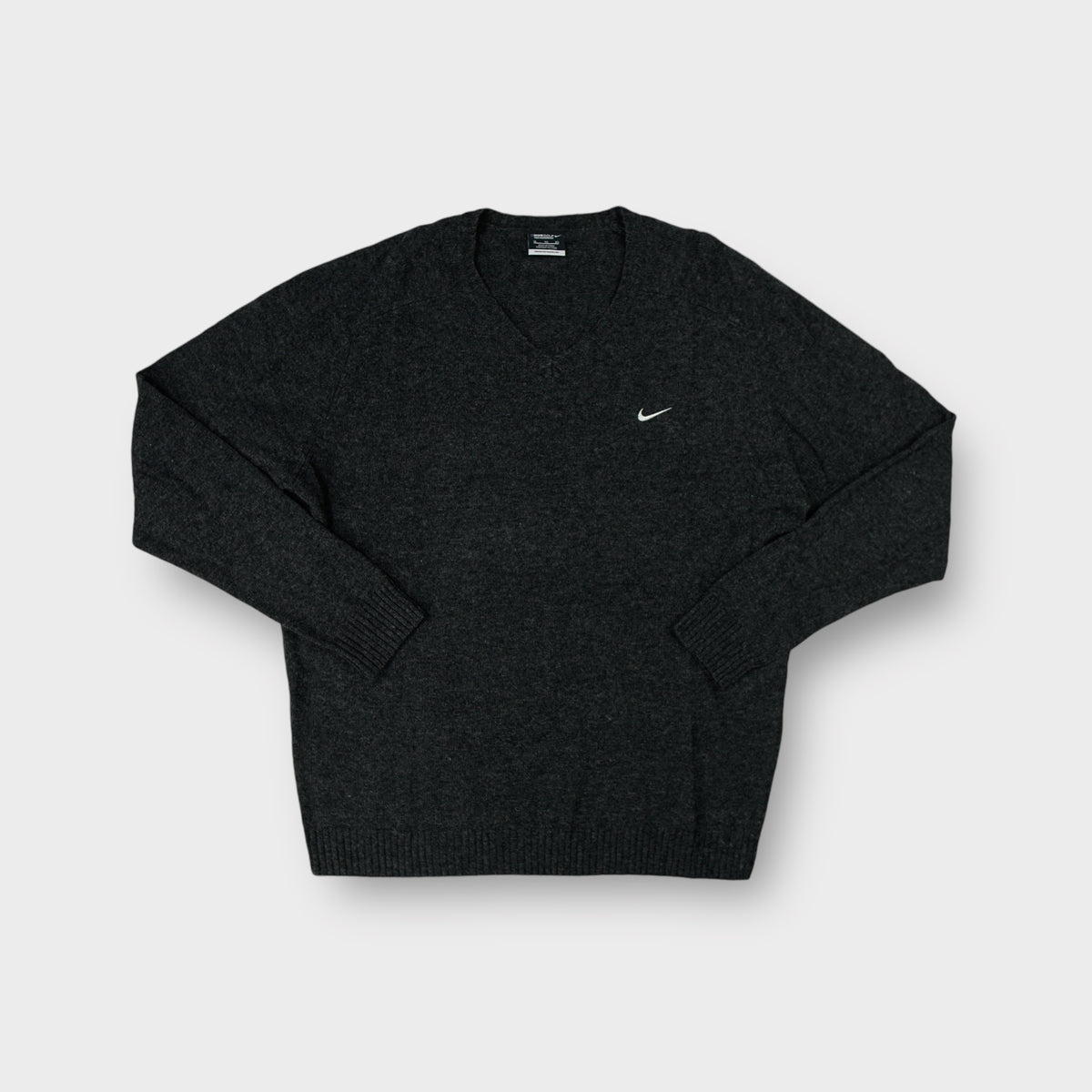 Nike Golf V-neck knit sweater in dark grey with an embroidered white swoosh on the chest.