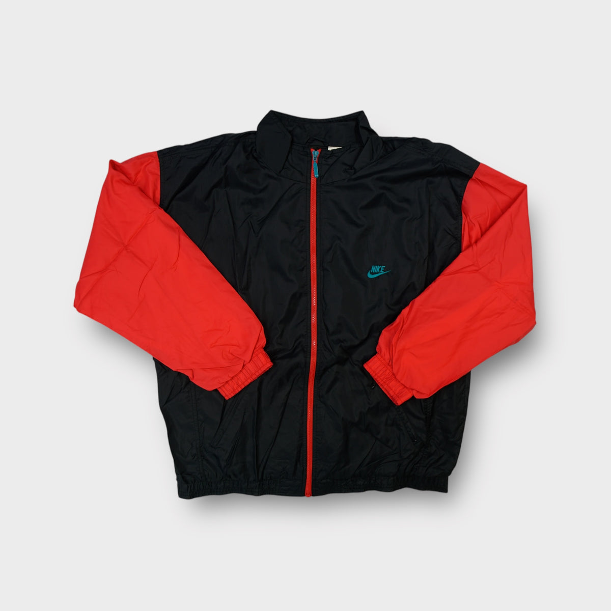 Nike track jacket in black and red featuring a teal embroidered chest logo and red front zip