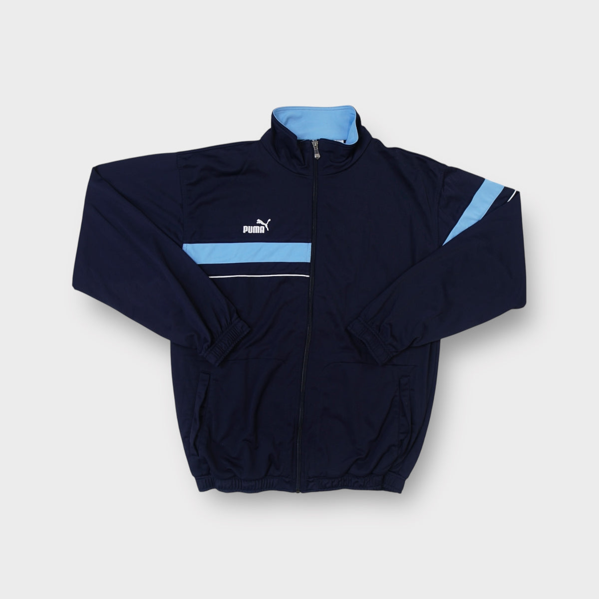 Puma black track jacket featuring a light blue chest panel and embroidered logo