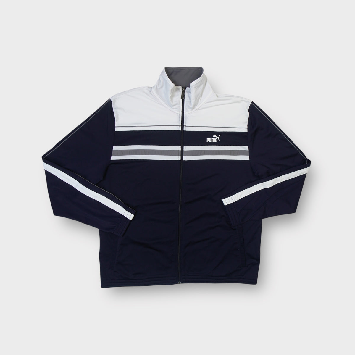 Puma full-zip track jacket in black featuring white chest panels and embroidered cat logo.