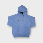 Champion pullover hoodie in light blue featuring an embroidered script chest logo.