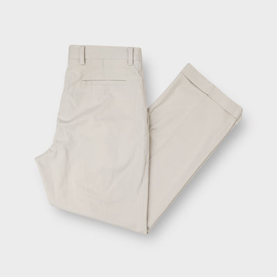 Nike beige golf trousers featuring front pleats and folded cuffed hems