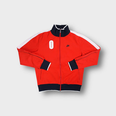 Red Nike track jacket with high collar, embroidered chest logo, and white shoulder stripes