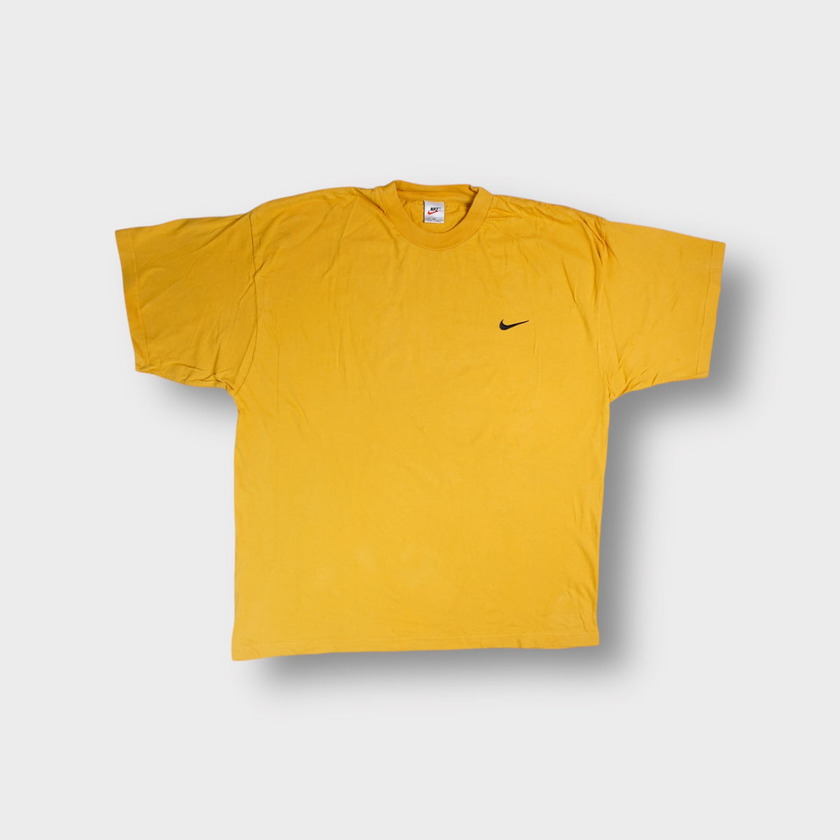 Yellow Nike T-Shirt featuring a small black swoosh logo embroidered on the left chest.