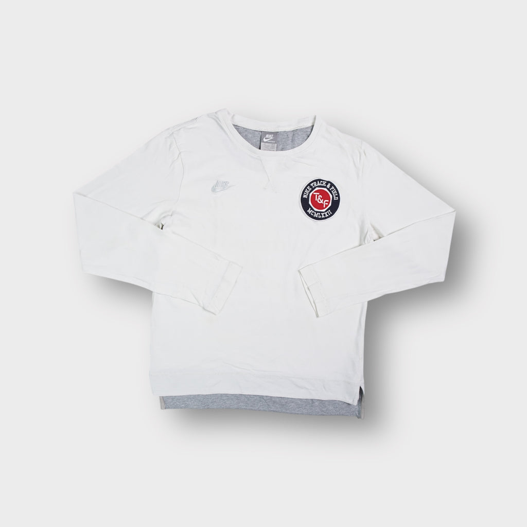 White Nike long-sleeve sweater featuring a round Track and Field logo patch