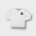 White Nike long-sleeve sweater featuring a round Track and Field logo patch