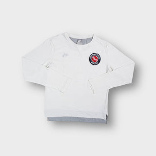 White Nike long-sleeve sweater featuring a round Track and Field logo patch