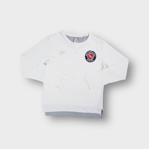 White Nike long-sleeve sweater featuring a round Track and Field logo patch