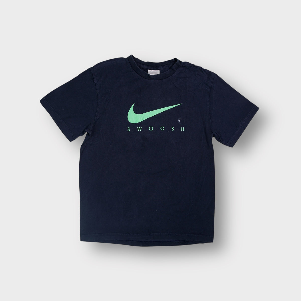 Nike T-Shirt in black featuring a green swoosh print across the chest