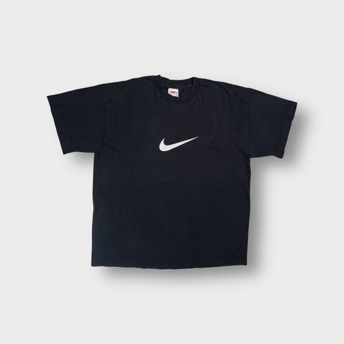 Nike T-Shirt in black featuring a printed white swoosh logo on the center chest