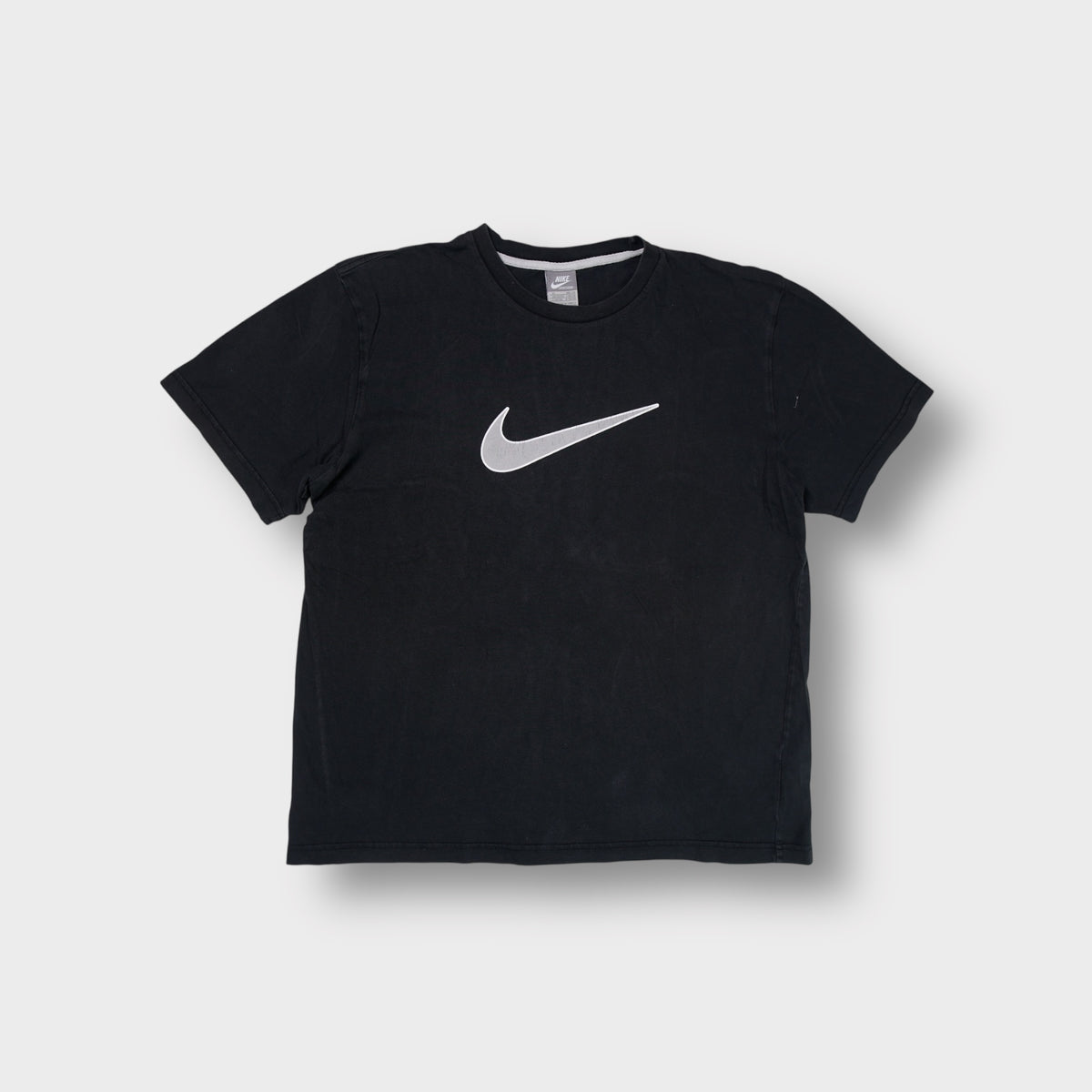 Nike short-sleeve T-Shirt in black featuring a large grey Swoosh printed on the chest