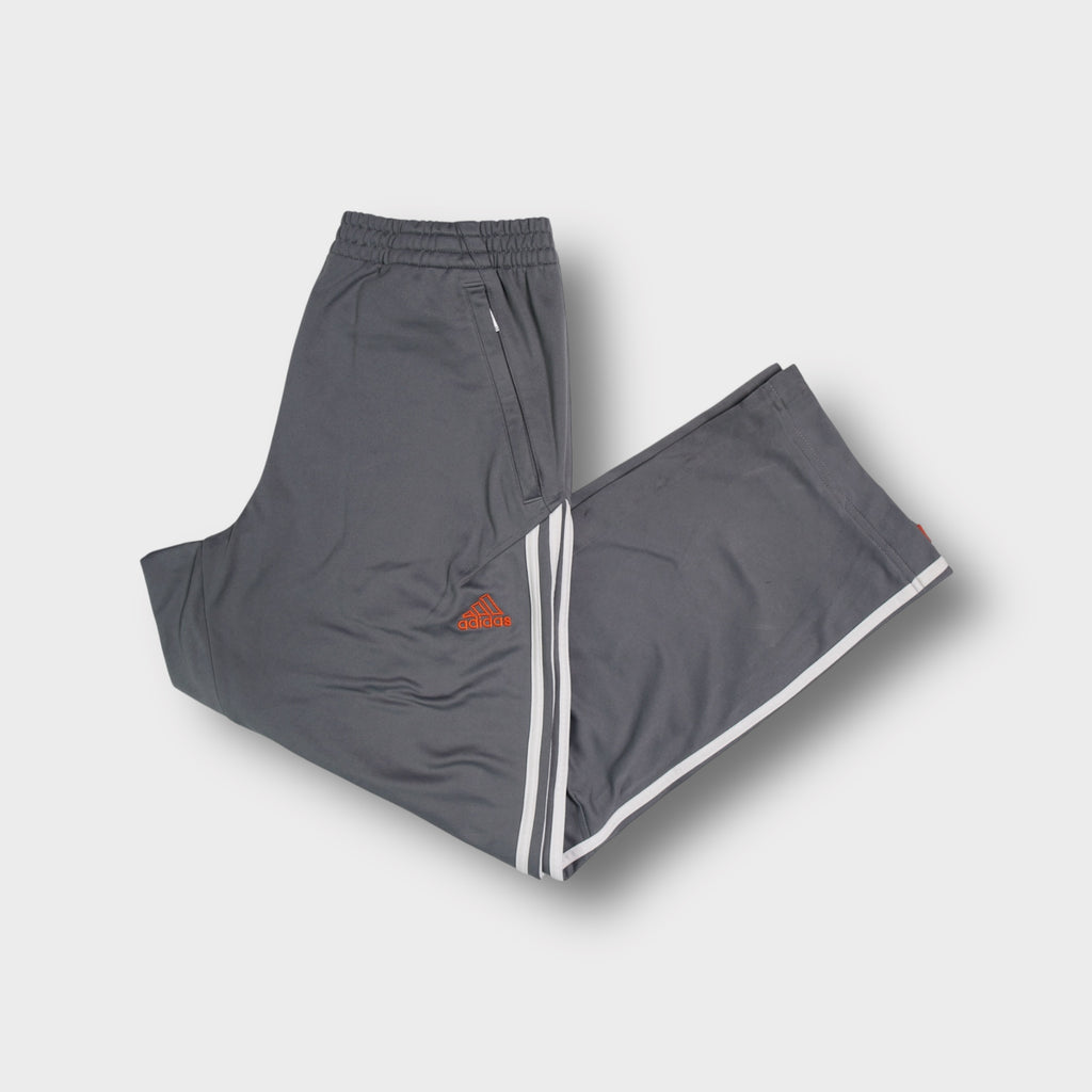 Adidas grey trackpants featuring white side stripes and an embroidered orange logo.