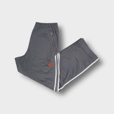 Adidas grey trackpants featuring white side stripes and an embroidered orange logo.