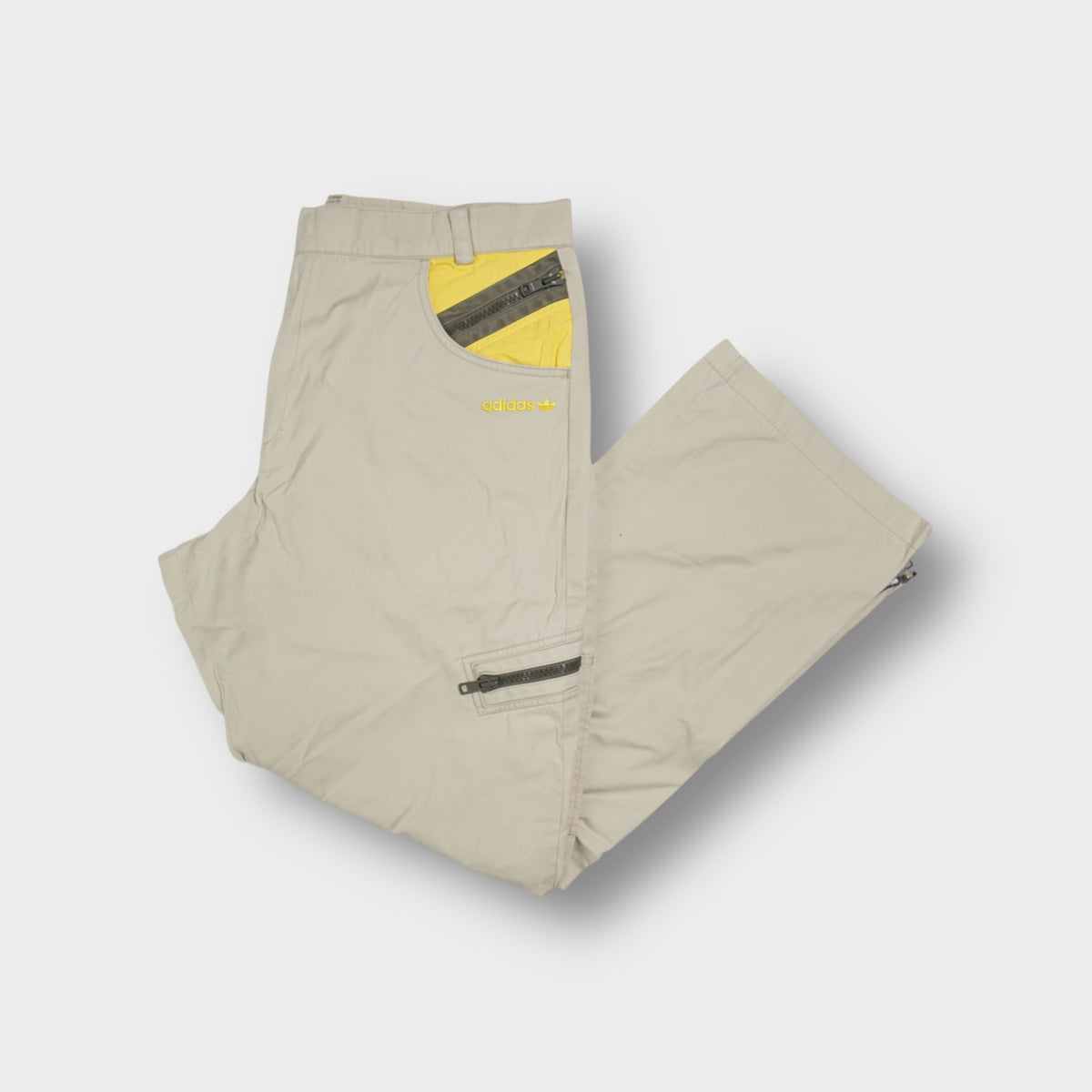 Adidas beige jeans featuring yellow pocket detailing and an embroidered logo