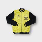 Adidas cycling track jacket in yellow and black with front chest logos and cyclist graphic.