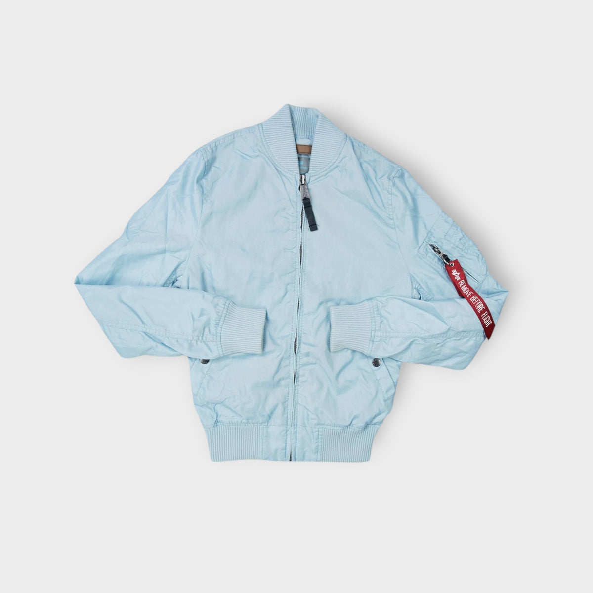 Alpha Industries bomber jacket in light blue with red Remove Before Flight tag on sleeve