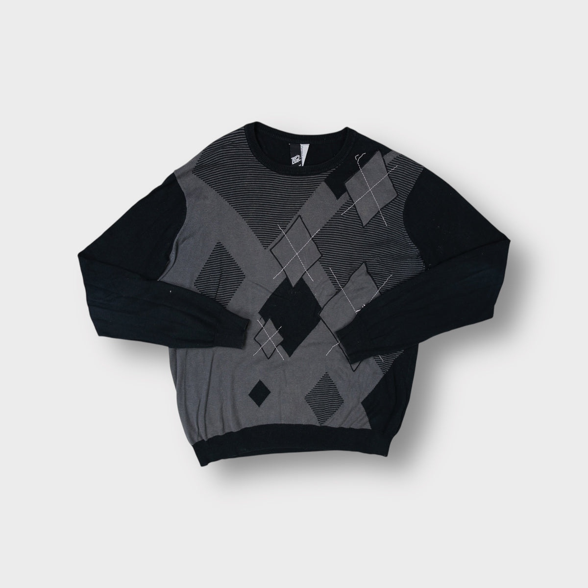 Rip Curl black knit sweater with a grey argyle pattern across the front