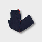 Nike women's trackpants in blue featuring orange side piping and an embroidered white swoosh logo.