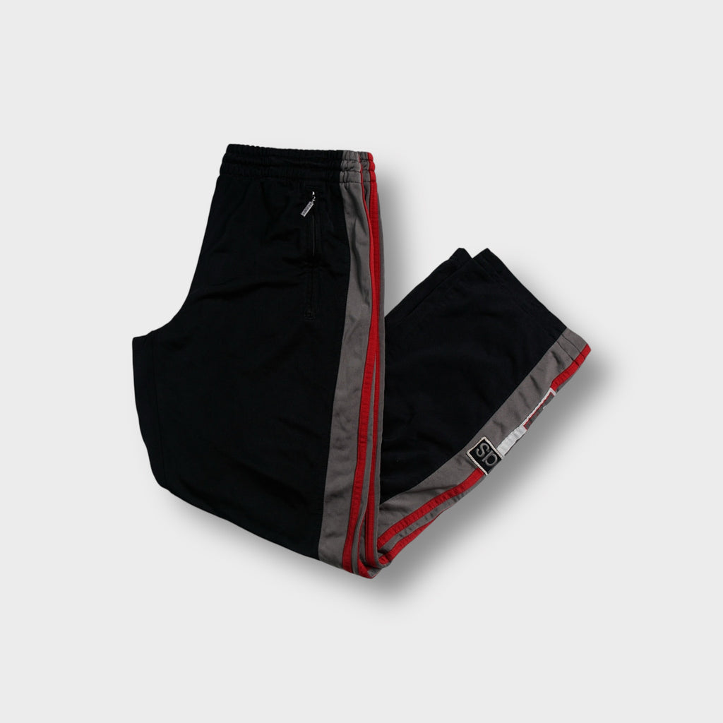 Adidas black trackpants featuring grey and red side stripes with ankle patches