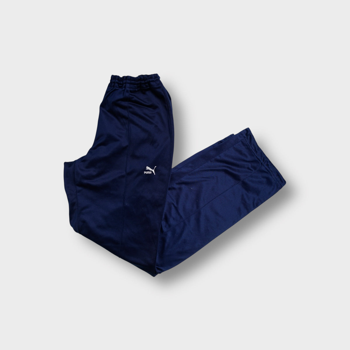 Blue Puma trackpants showing white embroidered cat logo on the left leg.