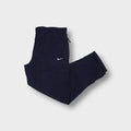 Nike trackpants in dark blue featuring a small white embroidered swoosh on the thigh