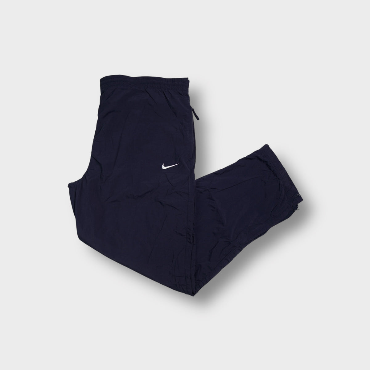 Nike trackpants in dark blue featuring a small white embroidered swoosh on the thigh