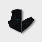 Black Adidas trackpants with side stripes, turquoise logo embroidery, and ribbed cuffs