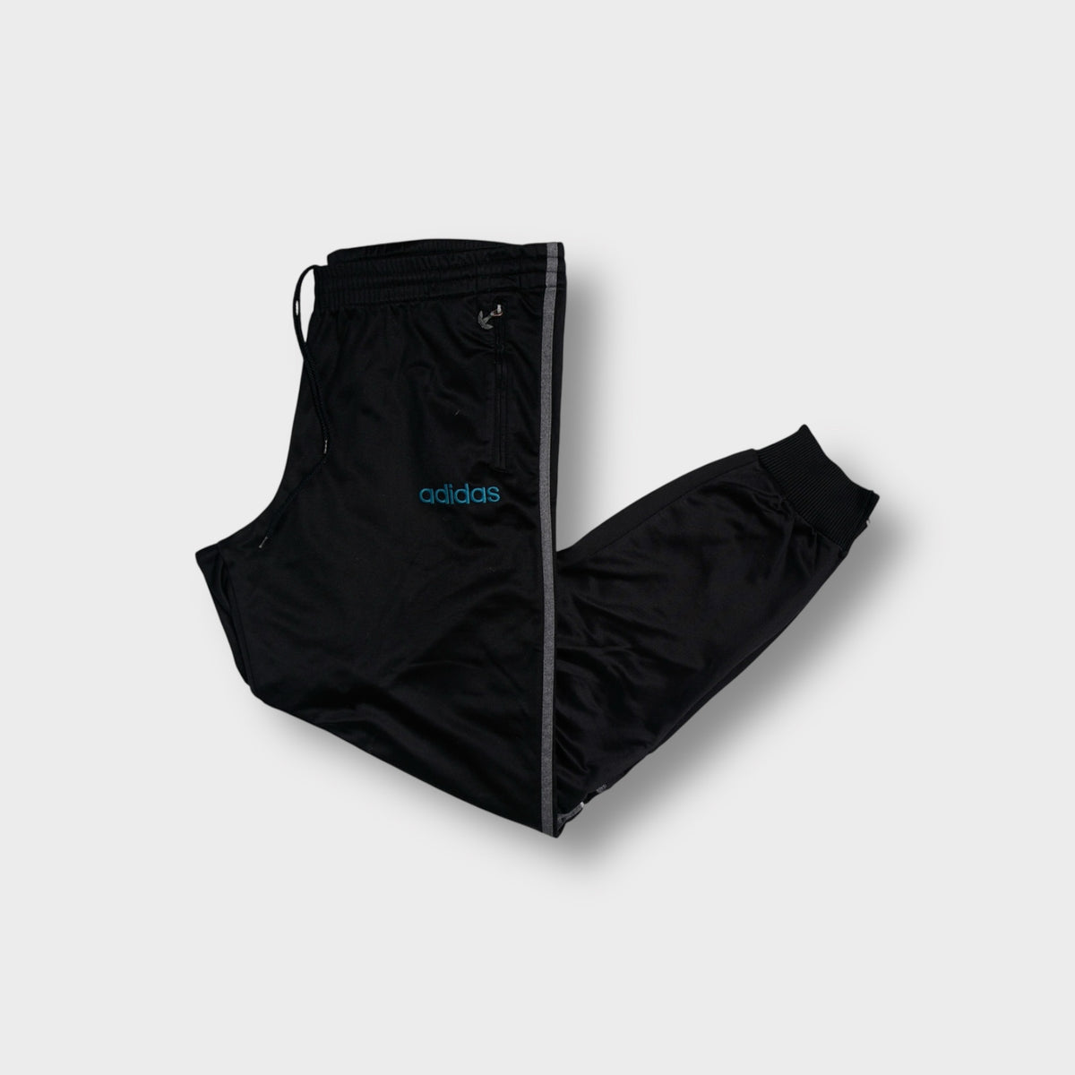 Black Adidas trackpants with side stripes, turquoise logo embroidery, and ribbed cuffs