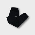 Black Nike trackpants featuring a white embroidered Swoosh logo on the upper leg