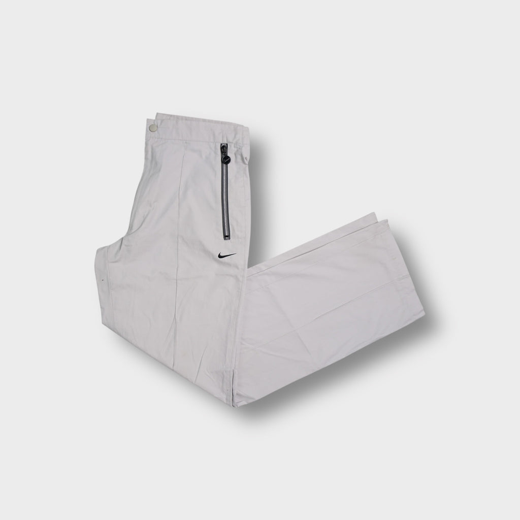 Beige Nike trackpants with exposed front zip pockets and embroidered swoosh logo