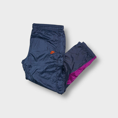 Blue Nike track pants with embroidered orange logo and purple lower leg accents