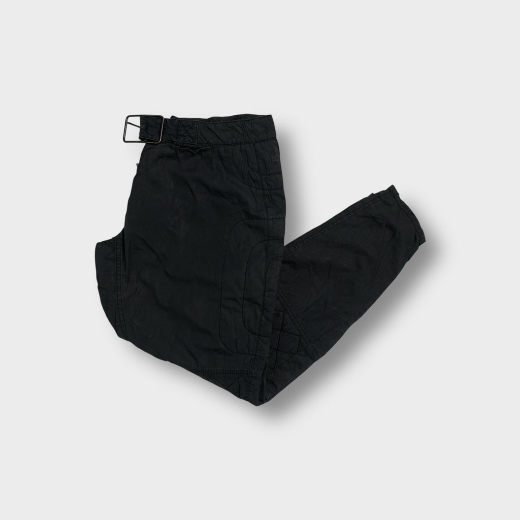 Black Prada pants with quilted knee patches and an adjustable waist buckle.