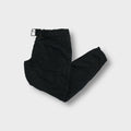 Black Prada pants with quilted knee patches and an adjustable waist buckle.